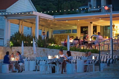 a group of people sitting at tables outside of a restaurant at Tara's Lodge Hotel in Korčula