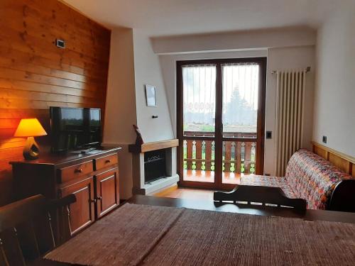 uma sala de estar com uma grande janela e uma televisão em Residence Weissthor em Macugnaga