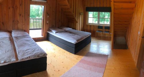 Habitación de madera con 2 camas y 2 ventanas en Emajõe puhkemaja, en Sarakuste