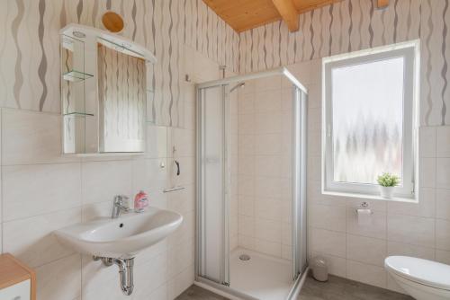 een witte badkamer met een wastafel en een douche bij Ferienhaus Natzel in Darlingerode