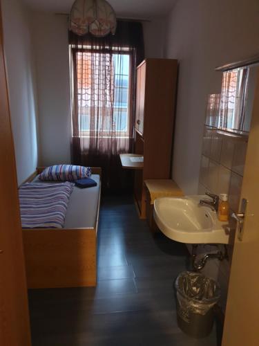 a small bathroom with a bed and a sink at Pension Engel in Pfullendorf