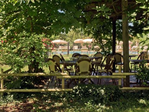 a group of tables and chairs under a tree at Hotel-Restaurant Le Moulin De La Camandoule in Fayence