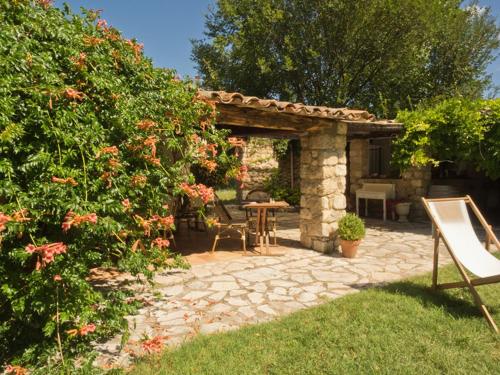 a patio with a table and a bench in a garden at Hotel-Restaurant Le Moulin De La Camandoule in Fayence