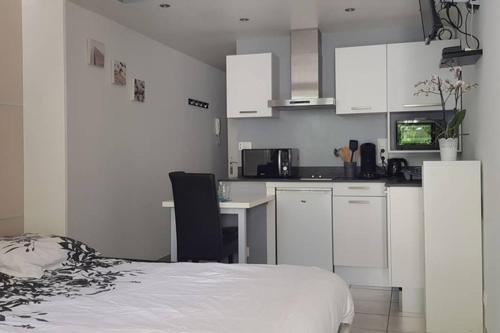 une cuisine avec des armoires blanches et un lit dans une chambre dans l'établissement Charmant studio 2* rdc+ terrasse & parking privé, à Aix-les-Bains