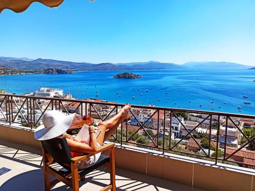 a couple sitting in a chair on a balcony overlooking the ocean at King Minos Hotel in Tolo