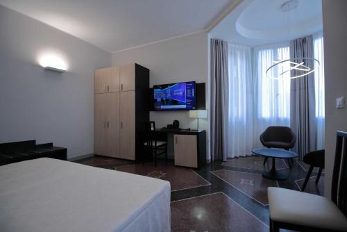a room with a bed and a desk and a television at Hotel Vittoria in Genova
