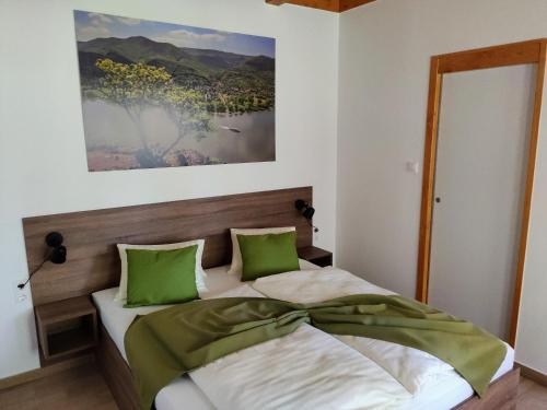 a bedroom with a bed with green pillows at Kishíd Vendégház Pilismarót in Pilismarót