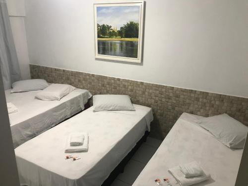 three beds in a room with a picture on the wall at Hotel Rota Dos Tropeiros in Castro