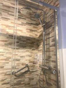 a shower in a bathroom with a stone wall at Alojamiento El Cantal in Santoña