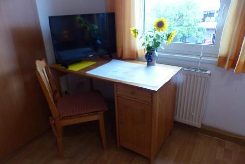a desk with a vase of flowers and a window at Pension Schreckhof in Mosbach