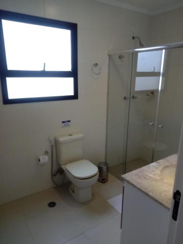 a bathroom with a toilet and a shower and a window at Conforto em Campos in Campos do Jordão
