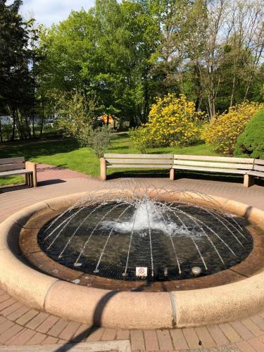 a fountain in a park with two park benches at Hotel zur Köppe in Bad Klosterlausnitz
