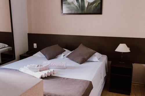 a bedroom with a bed with two towels on it at Alzira Granada Hotel in São Lourenço