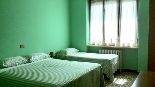 two beds in a room with green walls and a window at Albergo San Candido in Murisengo