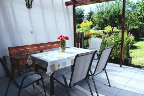 a table with chairs and a vase of flowers on a patio at Dom pod Górami in Mirsk