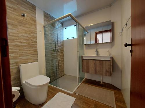 a bathroom with a toilet and a glass shower at San Michael Hospedaria in Treze Tílias