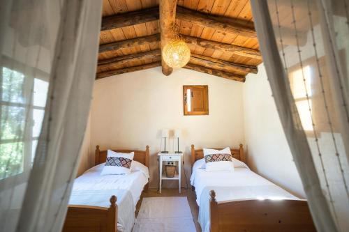 Duas camas num quarto com tectos em madeira em Finca el Moro - Casita del Cerro em Aracena