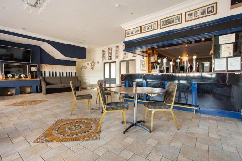 a dining room with a table and chairs and a bar at Beveridge Park Hotel in Kirkcaldy