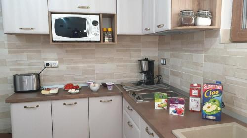 a kitchen with white cabinets and a microwave at NIKAS APARTMENT in Sibiu