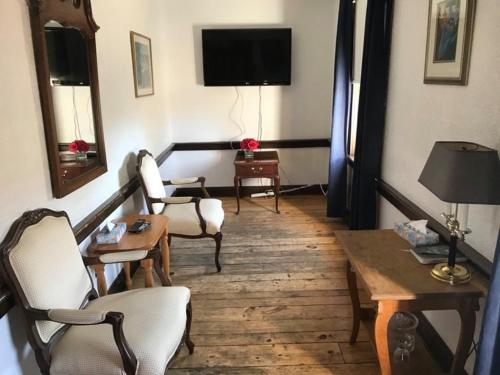 a living room with chairs and a table and a television at The Olde Angel Inn in Niagara on the Lake