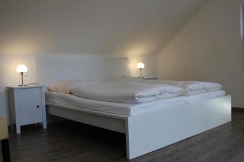 uma cama branca com duas luzes em cima em Pension Brunnenhof em Roetgen