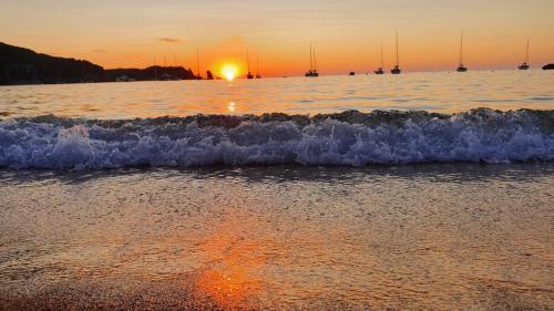 a sunset over the ocean with boats in the water at Campese Apartments in Campese