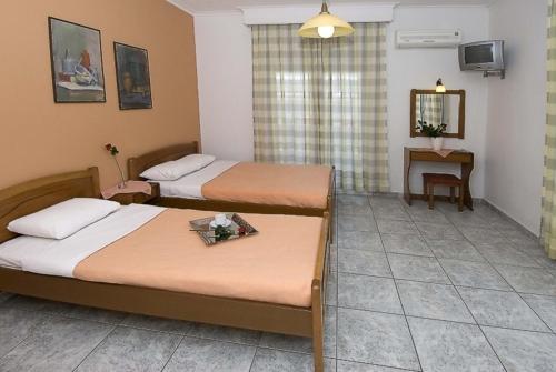 オリンピアキ・アクティにあるHarisis Apartmentsのベッド2台とテーブルが備わるホテルルームです。