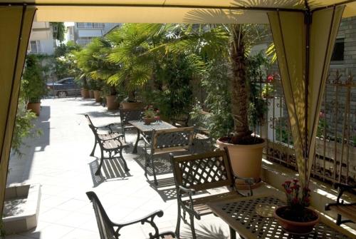 an outdoor patio with tables and chairs and palm trees at Harisis Apartments in Olympiaki Akti