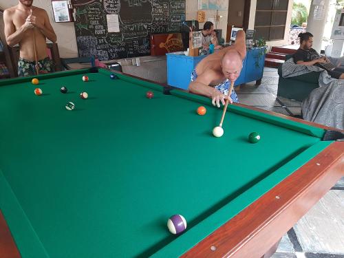 a man playing pool on a pool table at Tower Bridge Hostel in Puerto Escondido