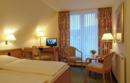 LügdeにあるLandhotel Lippischer Hofのベッド、デスク、椅子が備わるホテルルームです。