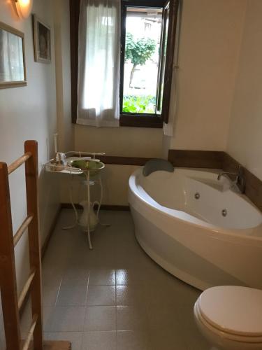 een badkamer met een bad, een toilet en een raam bij Maison Laurent in Courmayeur