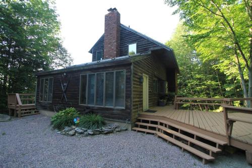 a small cabin with a wooden porch and a deck at Quaint Stowe Cabin in Stowe