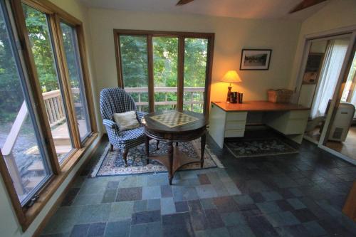 a living room with a desk and chairs and windows at Quaint Stowe Cabin in Stowe
