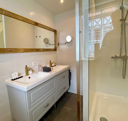 a bathroom with a sink and a mirror and a shower at Hotel Villa Verdi in Knokke-Heist