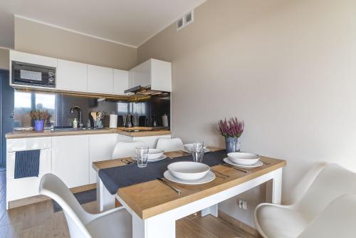 a kitchen with a wooden table with white chairs at Domki Złote Piaski Kryty Basen Sauna Jacuzzi in Jastrzębia Góra