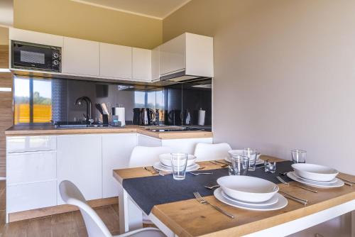 a kitchen with a table with plates and bowls on it at Domki Złote Piaski Kryty Basen Sauna Jacuzzi in Jastrzębia Góra