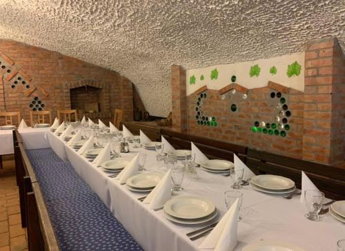 a long table with white plates and wine glasses at Liza Aqua & Conference Hotel in Lajosmizse