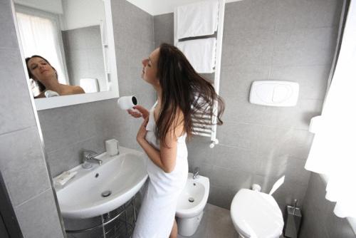 a woman standing in a bathroom brushing her teeth at Hotel La Pergola di Venezia in Venice-Lido