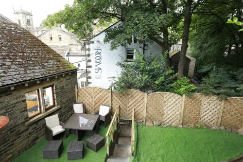 a backyard with a table and chairs and a fence at Higgin Bridge House in Holmfirth