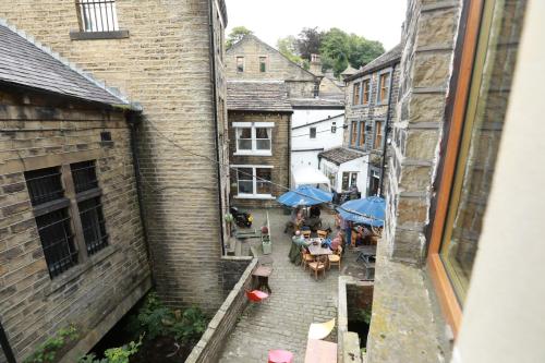 an alley with tables and umbrellas in a city at Higgin Bridge House in Holmfirth