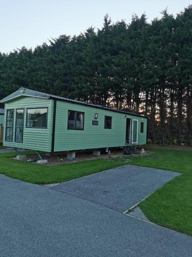 a green tiny house sitting on the grass at Rustling Pines at Knaresborough Lido in Harrogate
