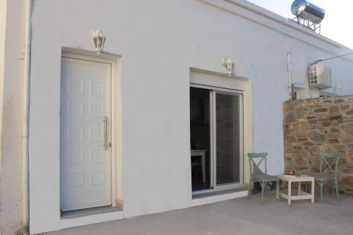 a white building with a door and two chairs at New and Airy Apartment few steps from the beach in Sougia