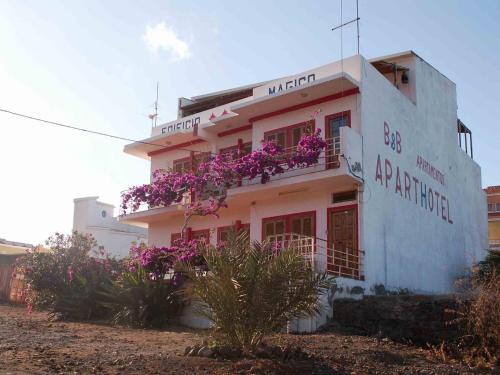a white building with purple flowers in front of it at Edificio Magico in Tarrafal