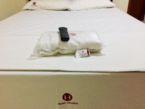 a bed with a remote control on top of it at Hotel Oliveira - By UP Hotel in Ipatinga