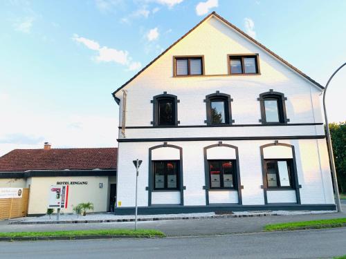 a white building with black windows on a street at Hotel Royal in Leopoldshöhe