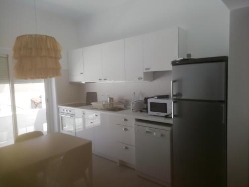 a kitchen with white cabinets and a black refrigerator at Casa do Jardim in Beja
