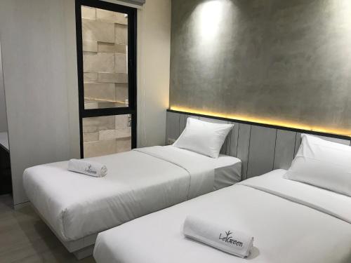 two beds in a hotel room with white sheets at LeGreen Suite Semanggi in Jakarta