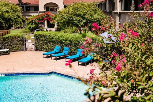 a group of blue chairs next to a swimming pool at Vineyard Court Designer Suites Hotel in College Station