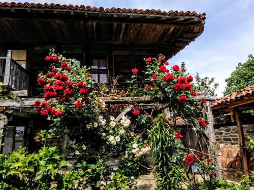 una casa vieja con flores rojas y blancas. en Къщата на художника, en Zheravna