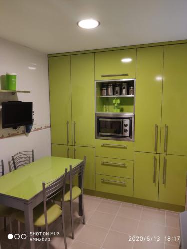 a green kitchen with a table and a microwave at Habitación individual con baño privado en casa particular in Madrid